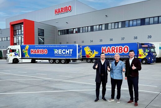 (Von links): Navid Thielemann, CEO der ThielemannGroup, Stefan Sorce, Geschäftsführer der HARIBO Logistik, sowie Christian Flick, CEO der RECHT Logistik GmbH und COO der ThielemannGroup, stehen am HARIBO-Standort Grafschaft vor dem neuen E-LKW und einem weiteren HARIBO-LKW