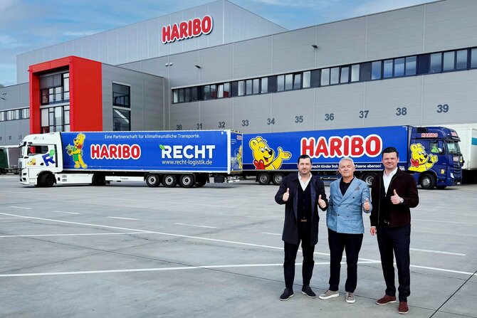 (Von links): Navid Thielemann, CEO der ThielemannGroup, Stefan Sorce, Geschäftsführer der HARIBO Logistik, sowie Christian Flick, CEO der RECHT Logistik GmbH und COO der ThielemannGroup, stehen am HARIBO-Standort Grafschaft vor dem neuen E-LKW und einem weiteren HARIBO-LKW