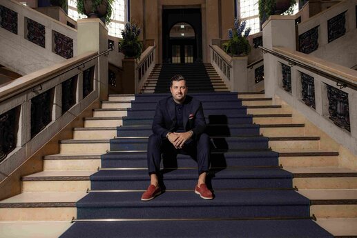 Navid Thielemann sitzt auf einer Treppe