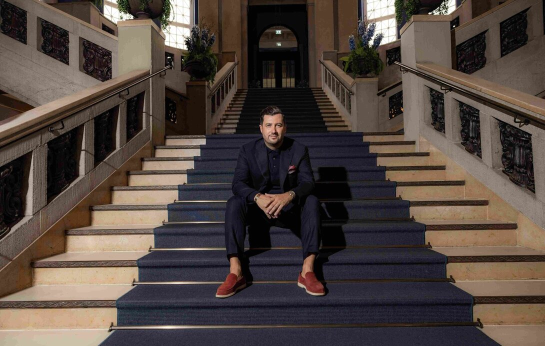 Navid Thielemann sitzt auf einer Treppe